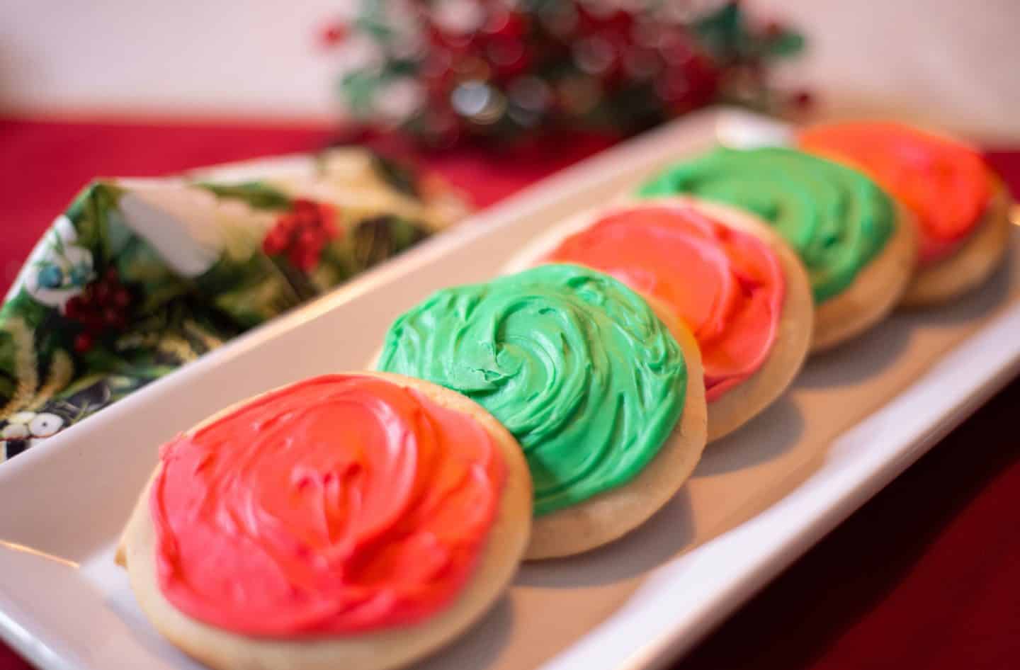 How to make traditional tea cakes with icing - A row of iced tea cakes in alternating red and green frosting, styled on a holiday platter. These Christmas cookies reflect soulful Southern tradition and visual appeal. Recipe and tips by Shaunda Necole & The Soul Food Pot®.