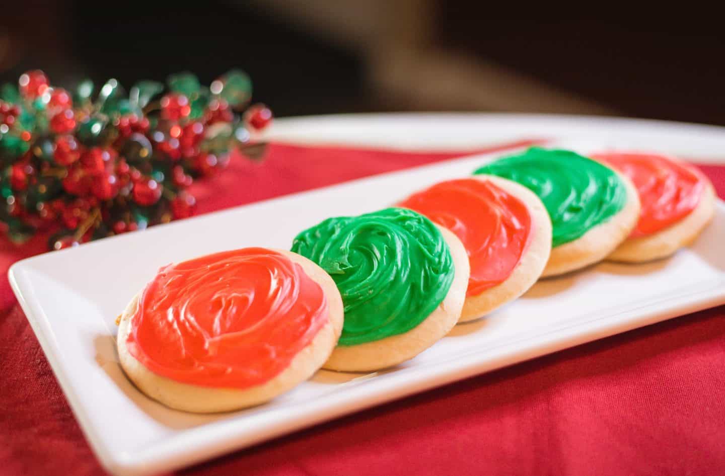 Shaunda's Soul Food Sense - texture, appearance, and tips for iced tea cakes - A holiday tray of iced Southern tea cakes, frosted in Christmas colors and set against red linens with seasonal decorations. Step-by-step homemade dessert from The Soul Food Pot®, honoring Black culinary heritage.