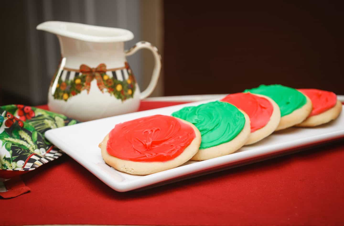 Why add icing to a traditional tea cake? - Classic Southern tea cakes topped with smooth red and green icing, served on a white platter with Christmas décor. A modern twist on Black folks’ tea cakes. Soulful holiday dessert by The Soul Food Pot®.