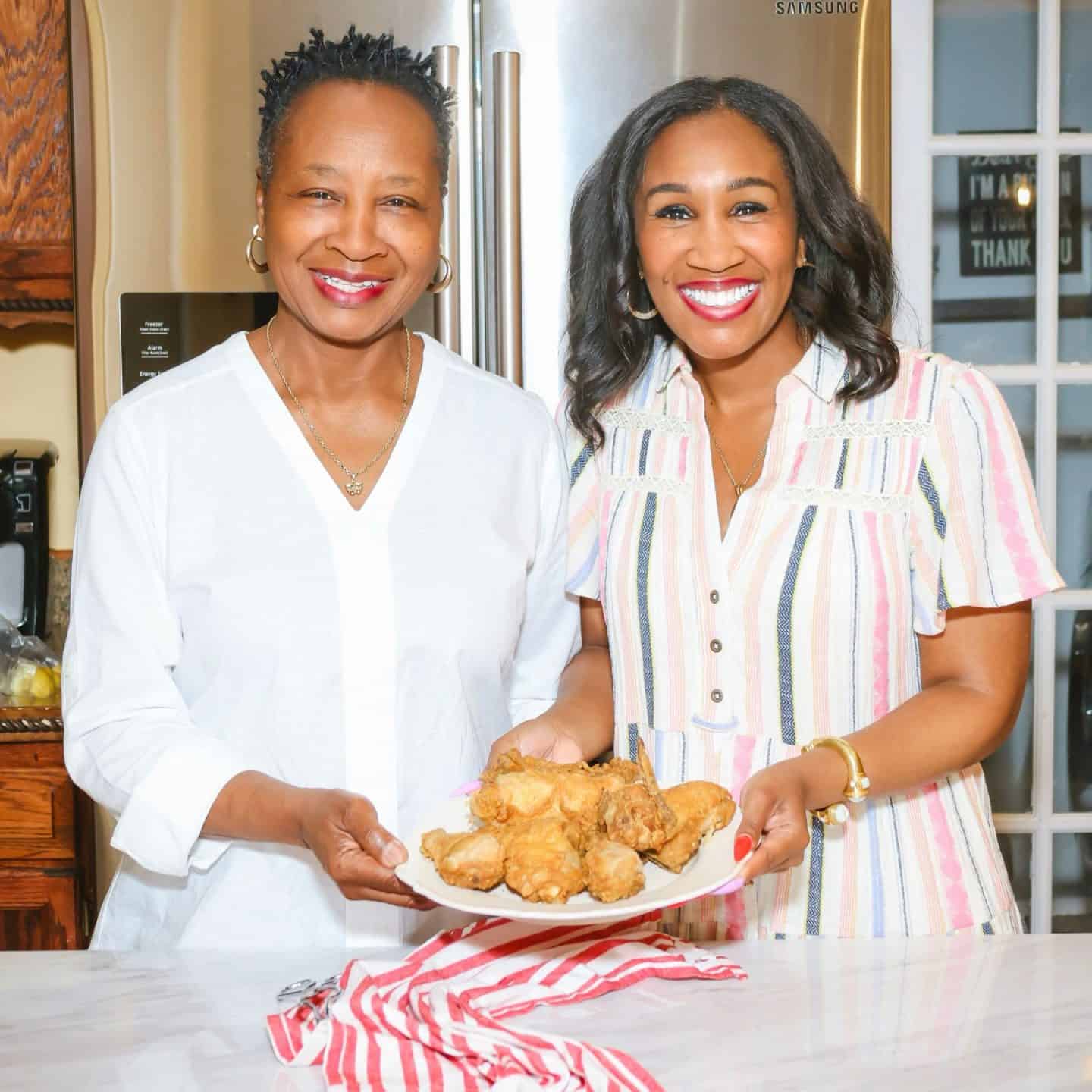 Shaunda Necole and her mother enjoying homemade Southern fried chicken in the kitchen — a generational moment highlighting authentic Black family recipes and the legacy of real soul food cooking at The Soul Food Pot®.