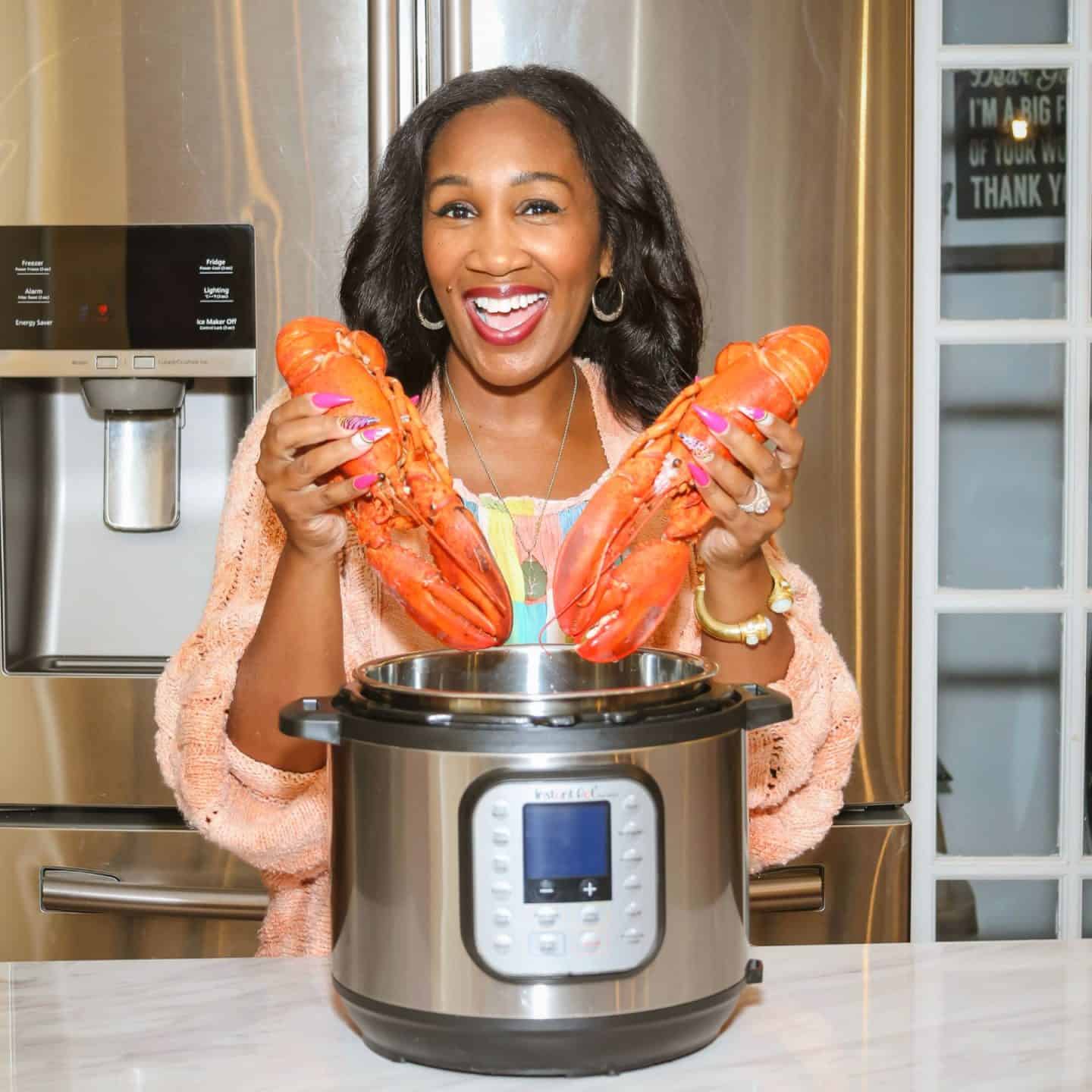 Shaunda Necole holding whole lobsters over a 6-quart Instant Pot in a home kitchen, demonstrating what size Instant Pot you need to cook lobster tails or whole lobster — a soul food–style Instant Pot lobster recipe from The Soul Food Pot®.