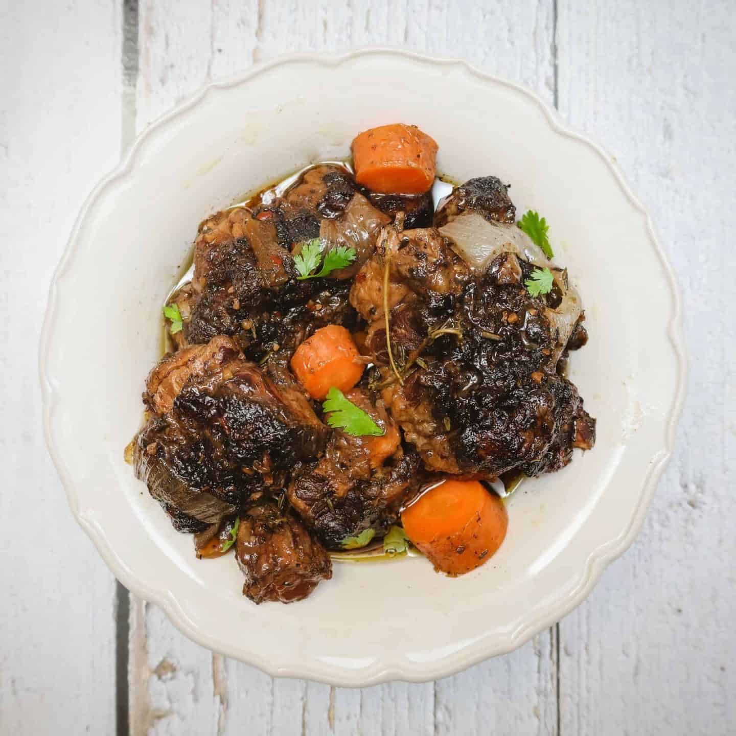 Black folks’ Instant Pot oxtail recipe served in a white bowl with tender, fall-off-the-bone oxtails in rich brown gravy with carrots and fresh herbs – The Soul Food Pot®