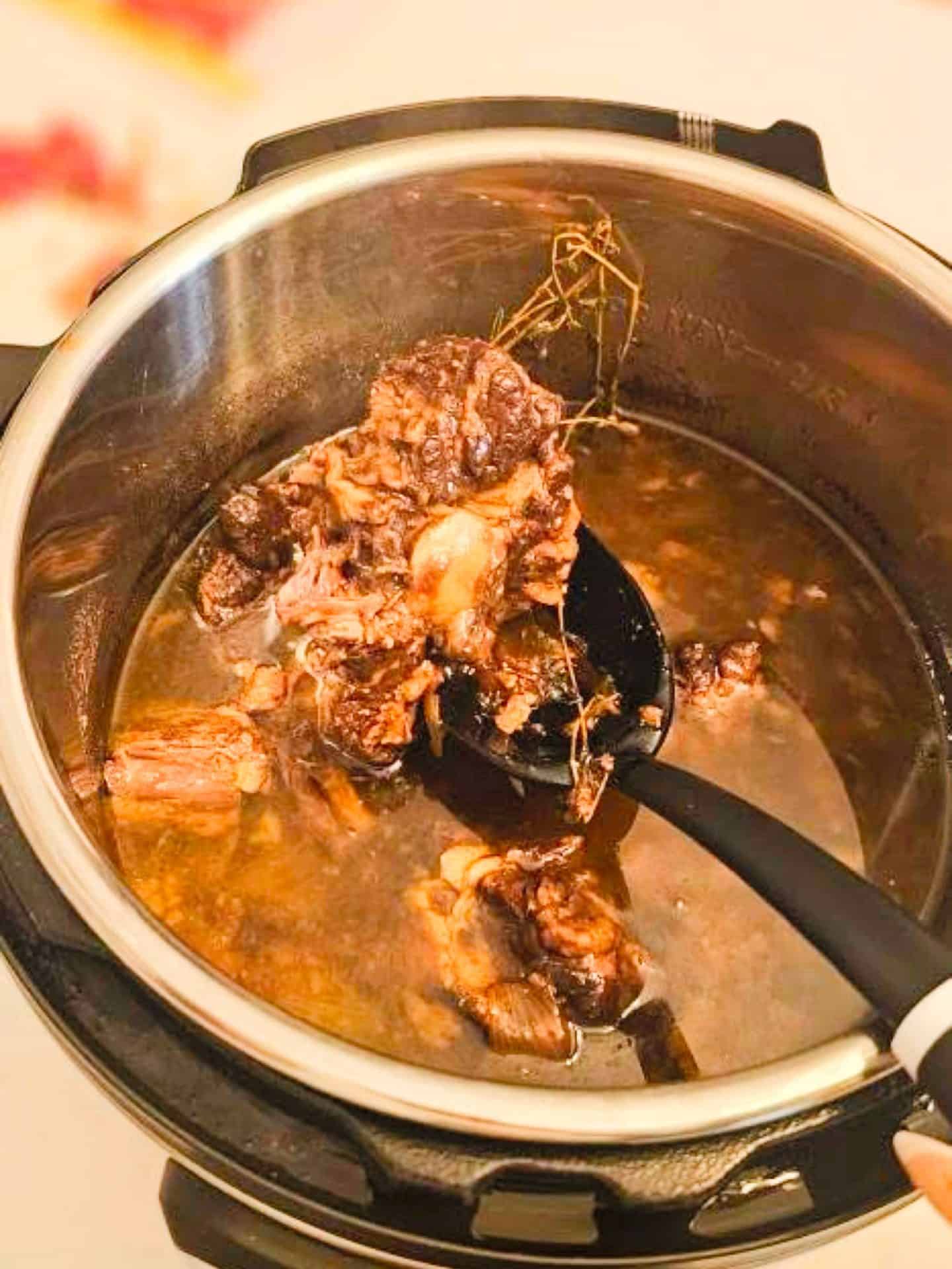 Oxtails cooking in the Instant Pot with broth and herbs – pressure cooking method for tender Black folks’ oxtail recipe by The Soul Food Pot®