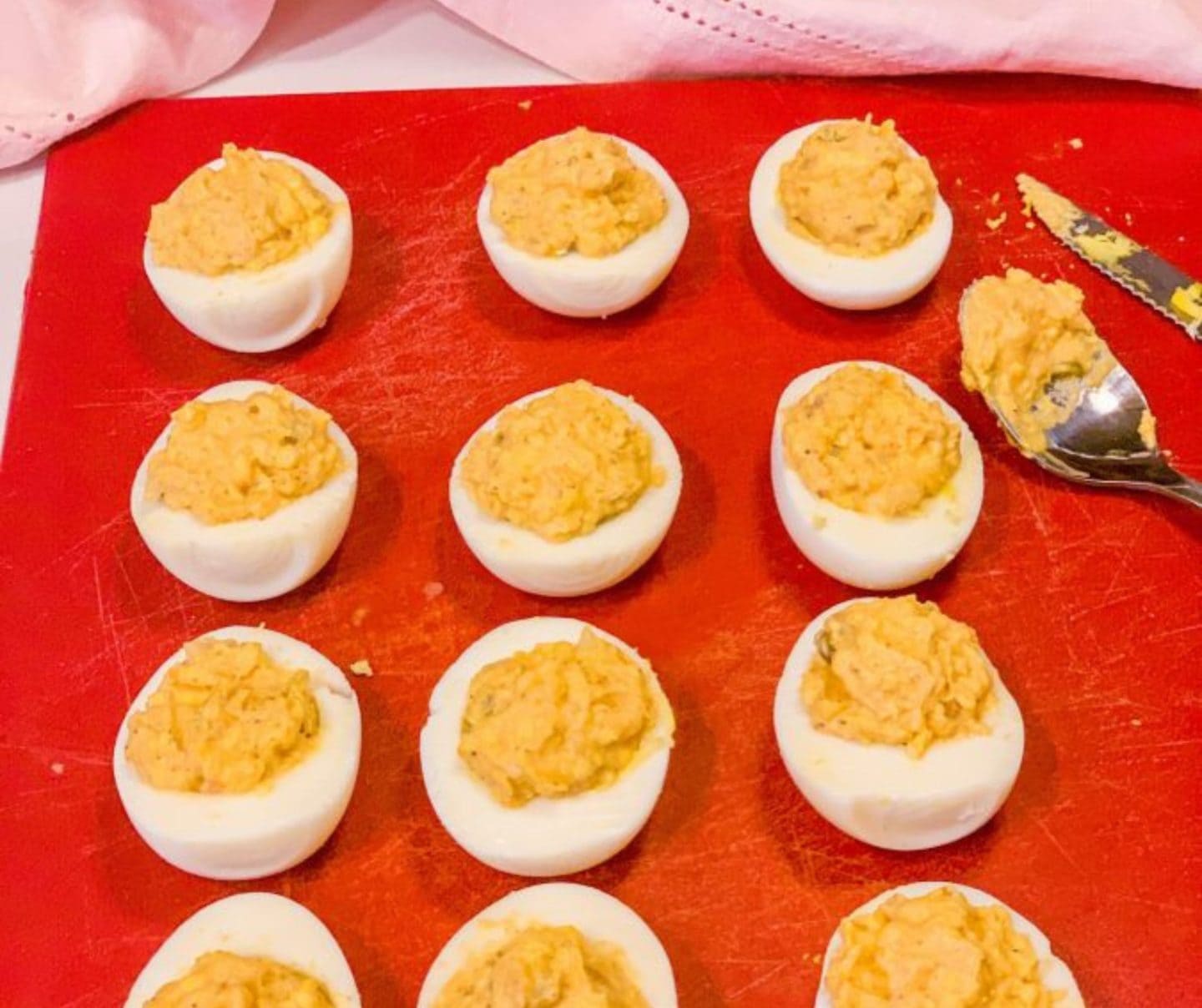 Deviled eggs filled with creamy yolk mixture before garnish, showing how to stuff deviled eggs the Black way using a spoon for a rustic Southern finish by The Soul Food Pot®
