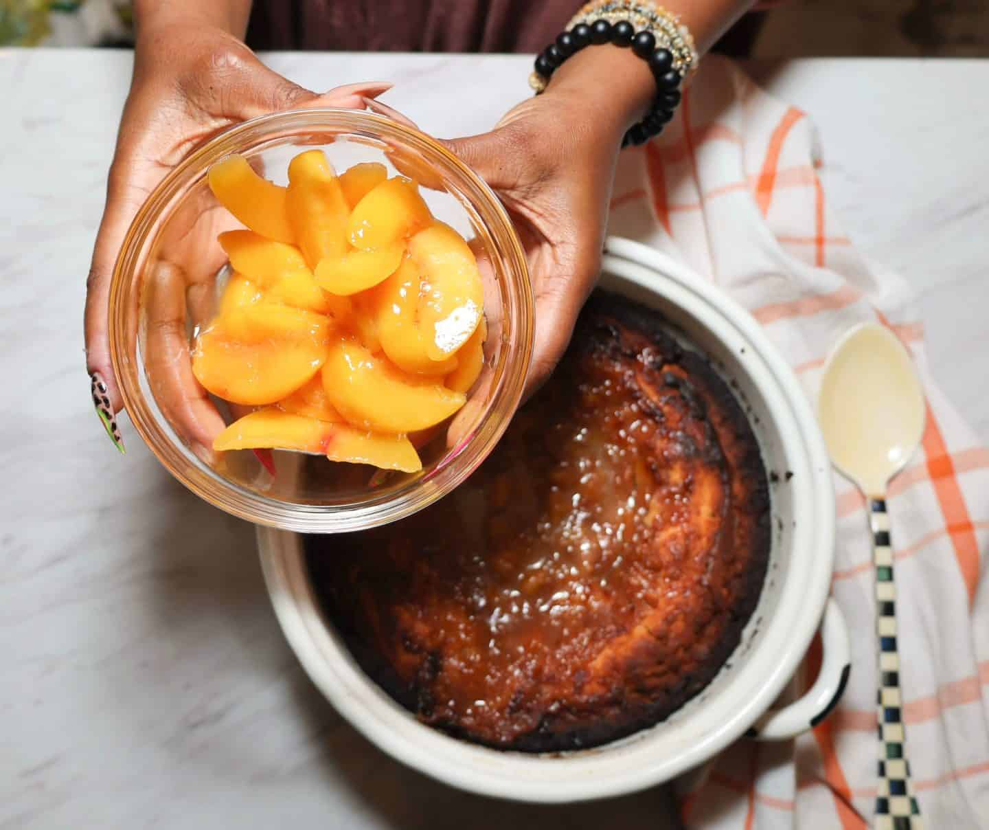 Shaunda Necole holding sliced frozen peaches for Southern peach cobbler, an easy Labor Day dessert option from The Soul Food Pot®.