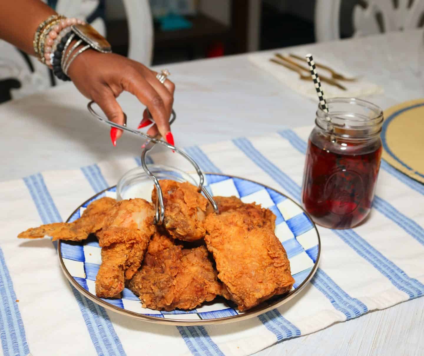 Shaunda Necole serving crispy Southern fried chicken from a platter with a glass of sweet tea, for The Soul Food Pot®.