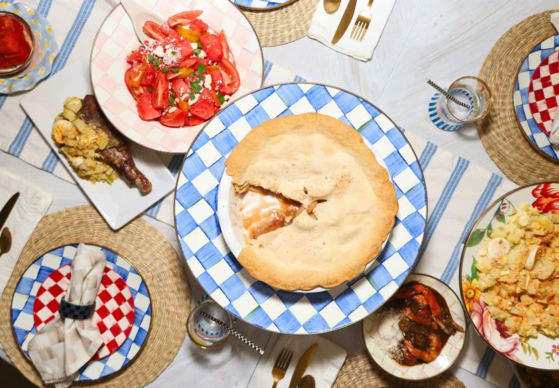 Shaunda’s Southern soul food apple pie served at a dinner table with classic gumbo, including turkey legs, potato salad, and a fresh tomato salad.