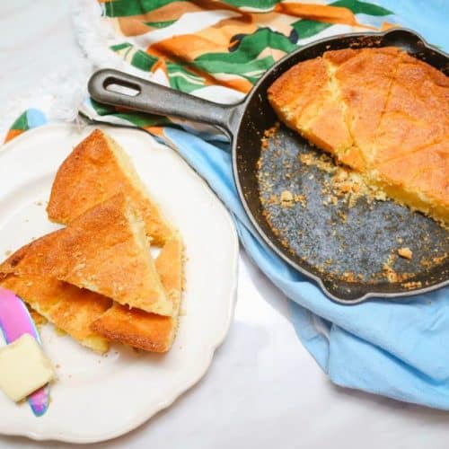 Cast-iron skillet cornbread with sliced wedges and butter