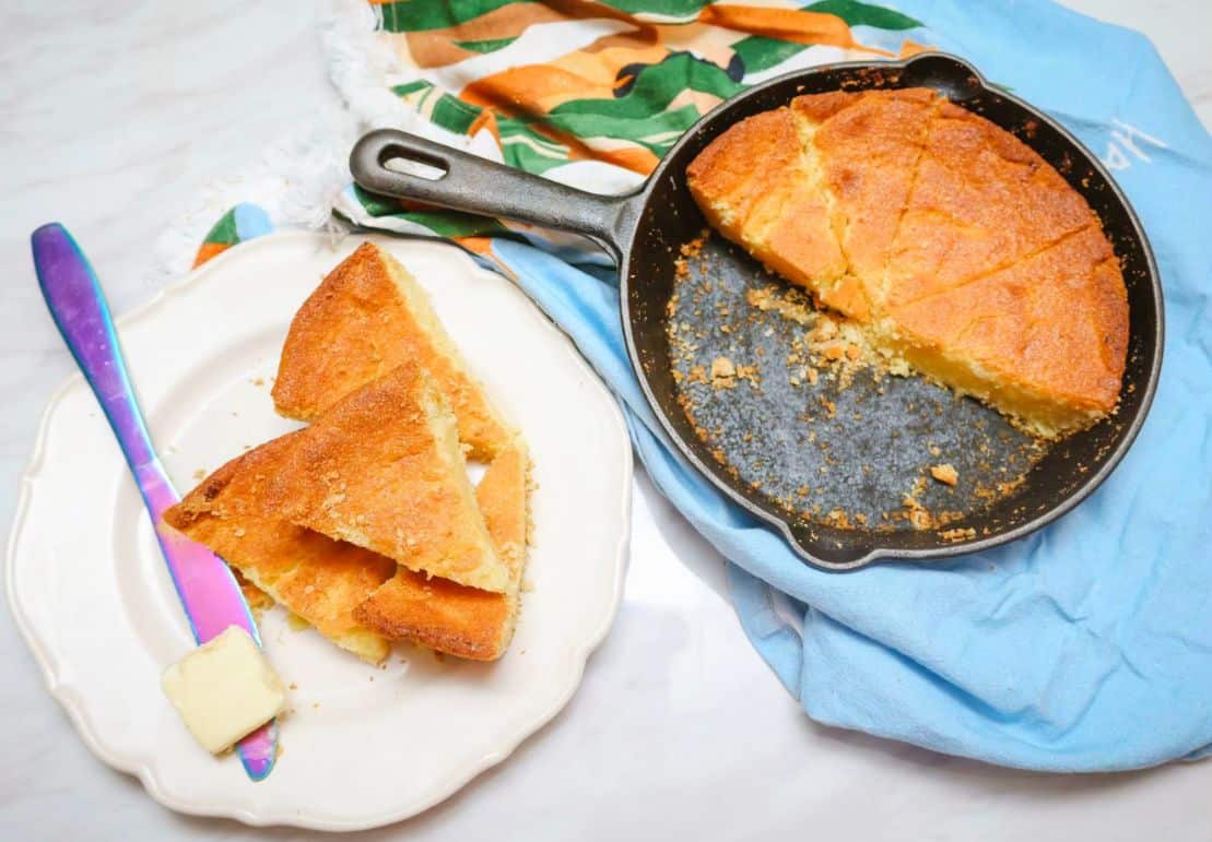 Cast-iron skillet cornbread with sliced wedges and butter