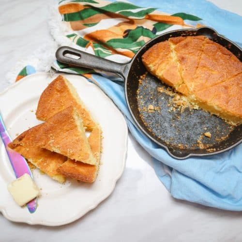 Cast-iron skillet cornbread with sliced wedges and butter
