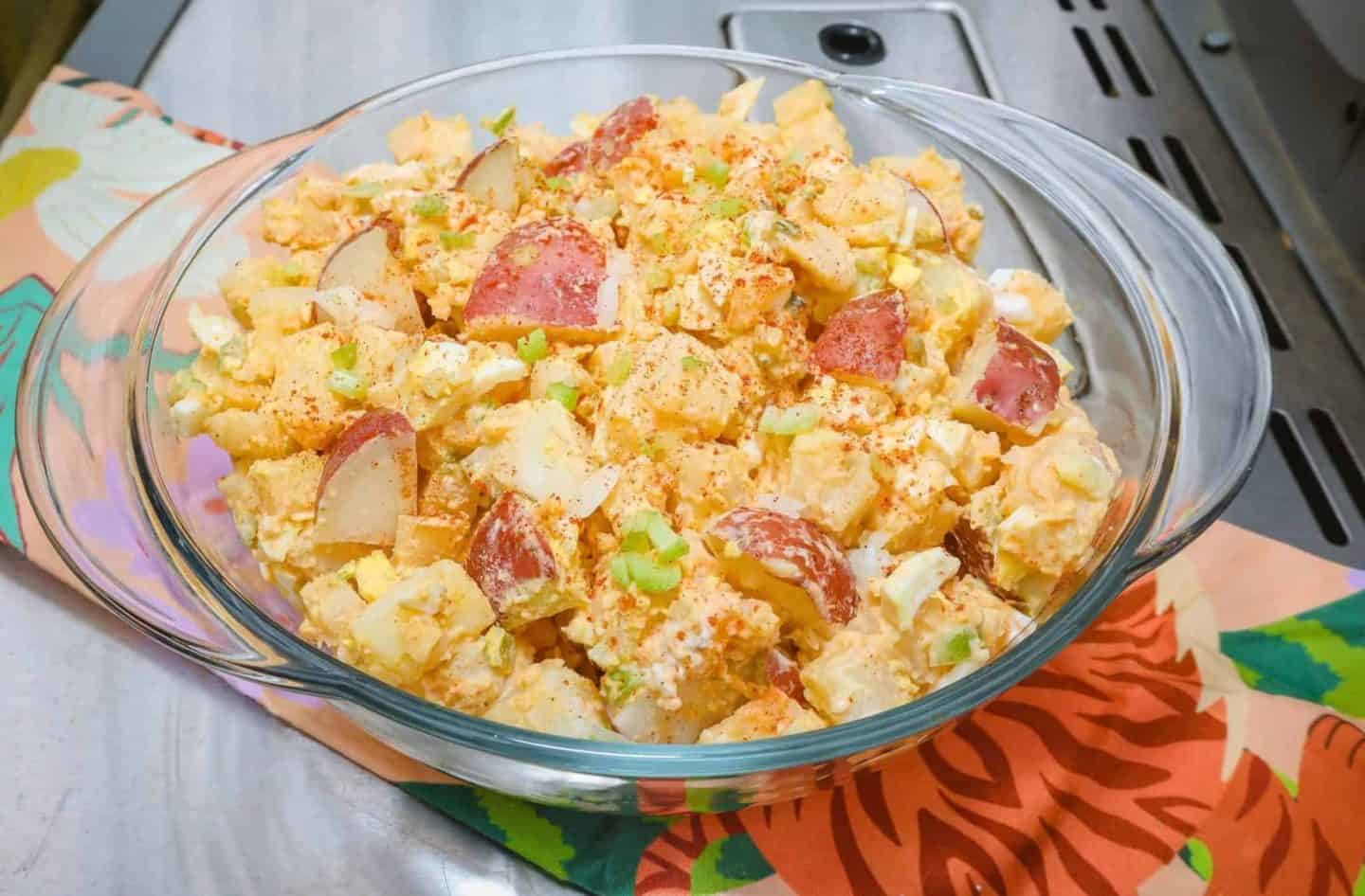 Close-up of The Soul Food Pot's creamy Southern potato salad with chunky red-skinned potatoes, chopped eggs, celery, and paprika in a glass serving dish.