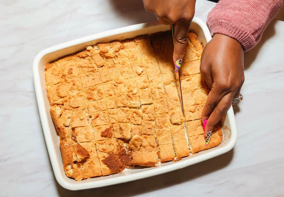 Homemade cornbread being cut into 1-inch cubes for The Soul Food Pot® Black folks chicken and dressing recipe.