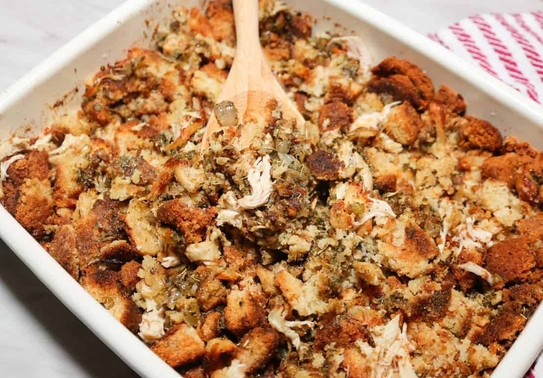 Close-up of The Soul Food Pot® Black folks chicken and dressing showing moist cornbread, tender shredded chicken, savory herbs, onion, and crisp golden edges.