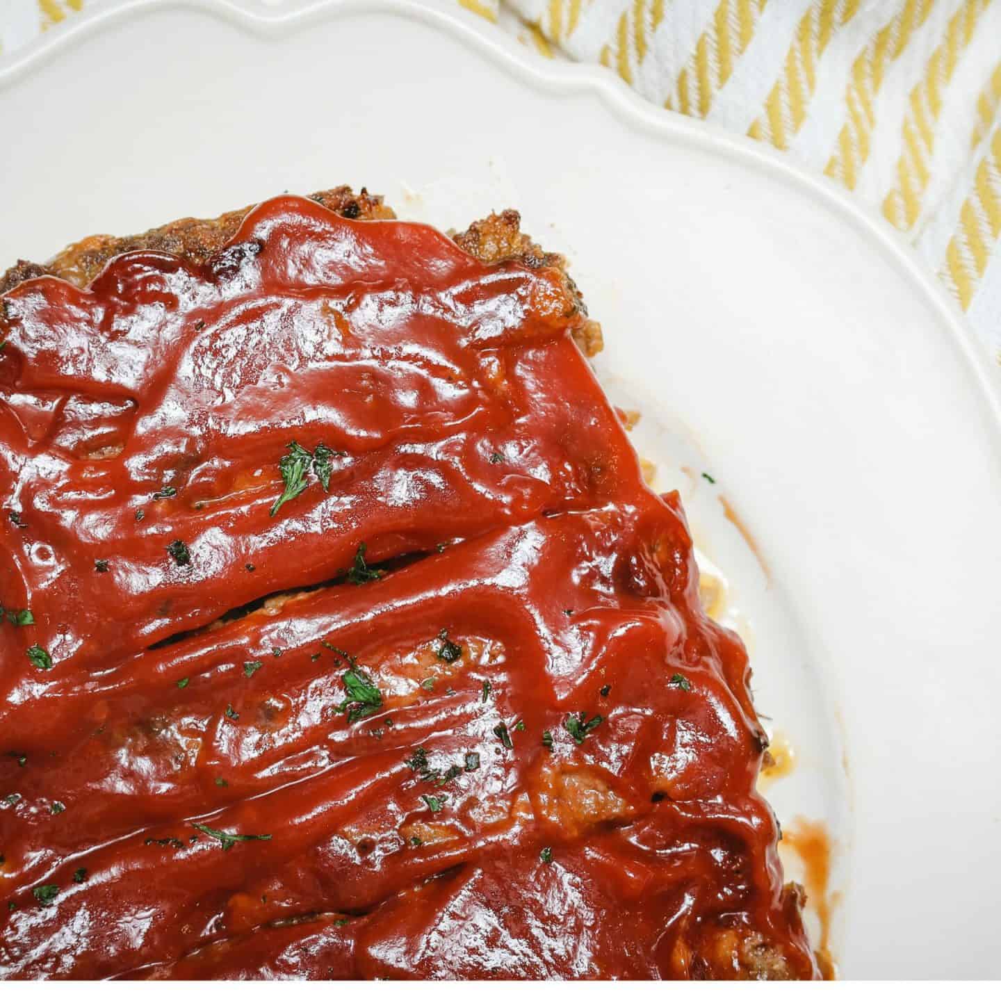 Homemade Southern meatloaf topped with a glossy tomato glaze and fresh herbs from The Soul Food Pot®.