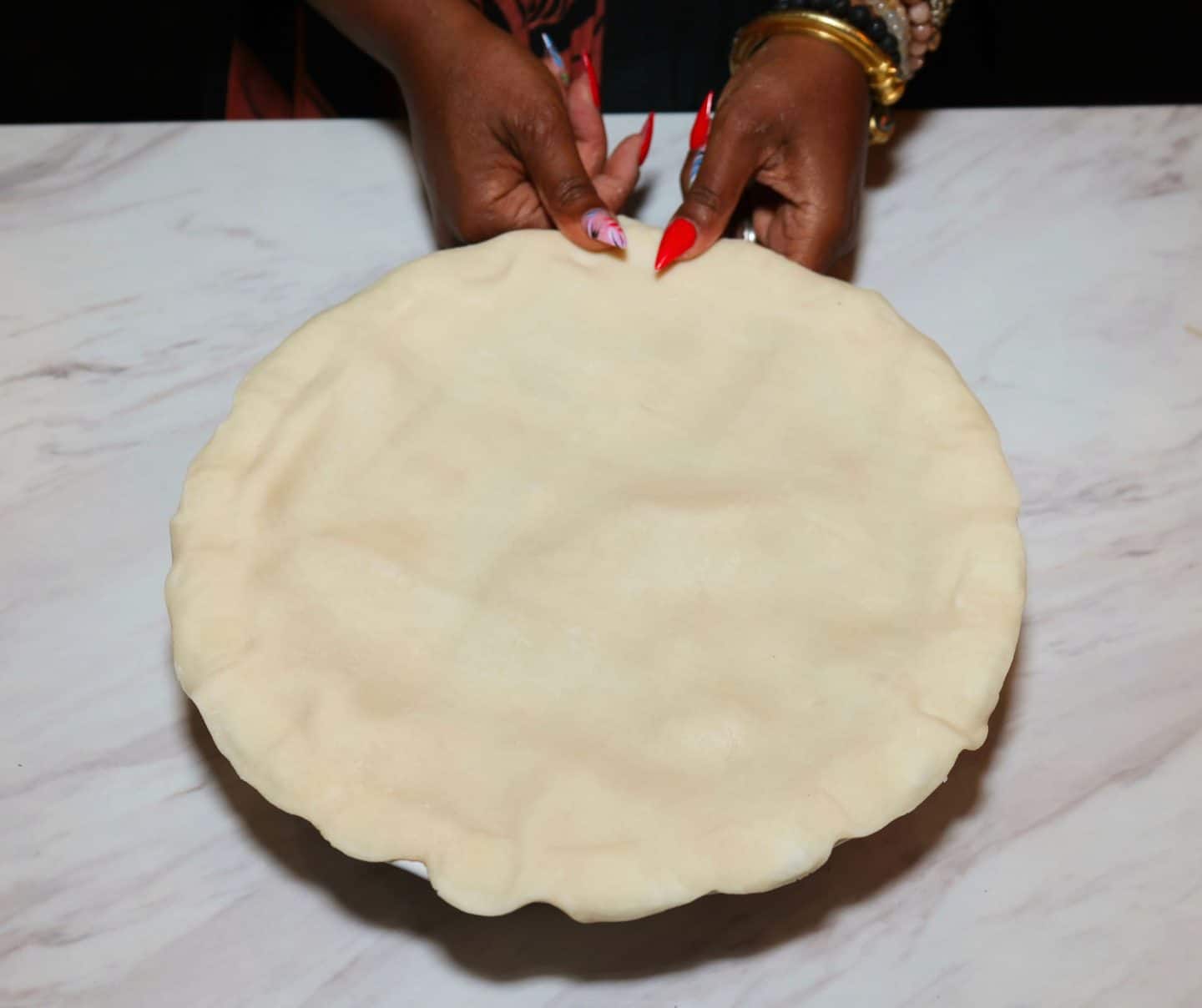 Shaunda Necole uses her fingertips to lightly crimp the edge of a homemade double-crust apple pie before baking for The Soul Food Pot®.