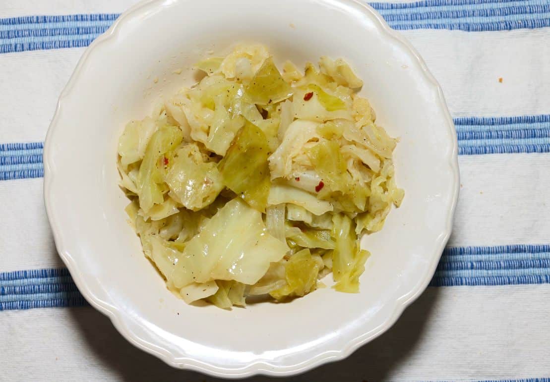 Southern cooked cabbage with tender green cabbage, onions, seasonings, and red pepper flakes in a white bowl from The Soul Food Pot®.