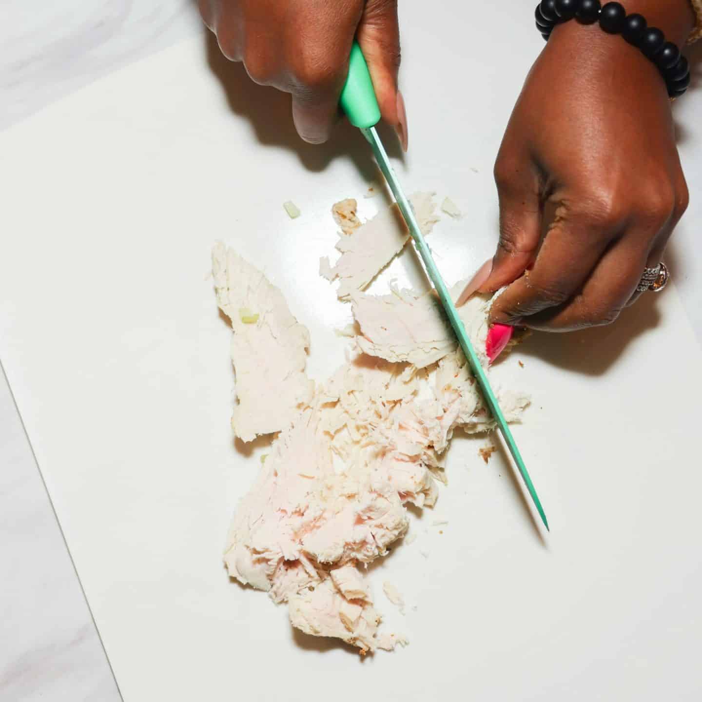Cooked chicken being cut into pieces for The Soul Food Pot® Black folks chicken and dressing recipe.
