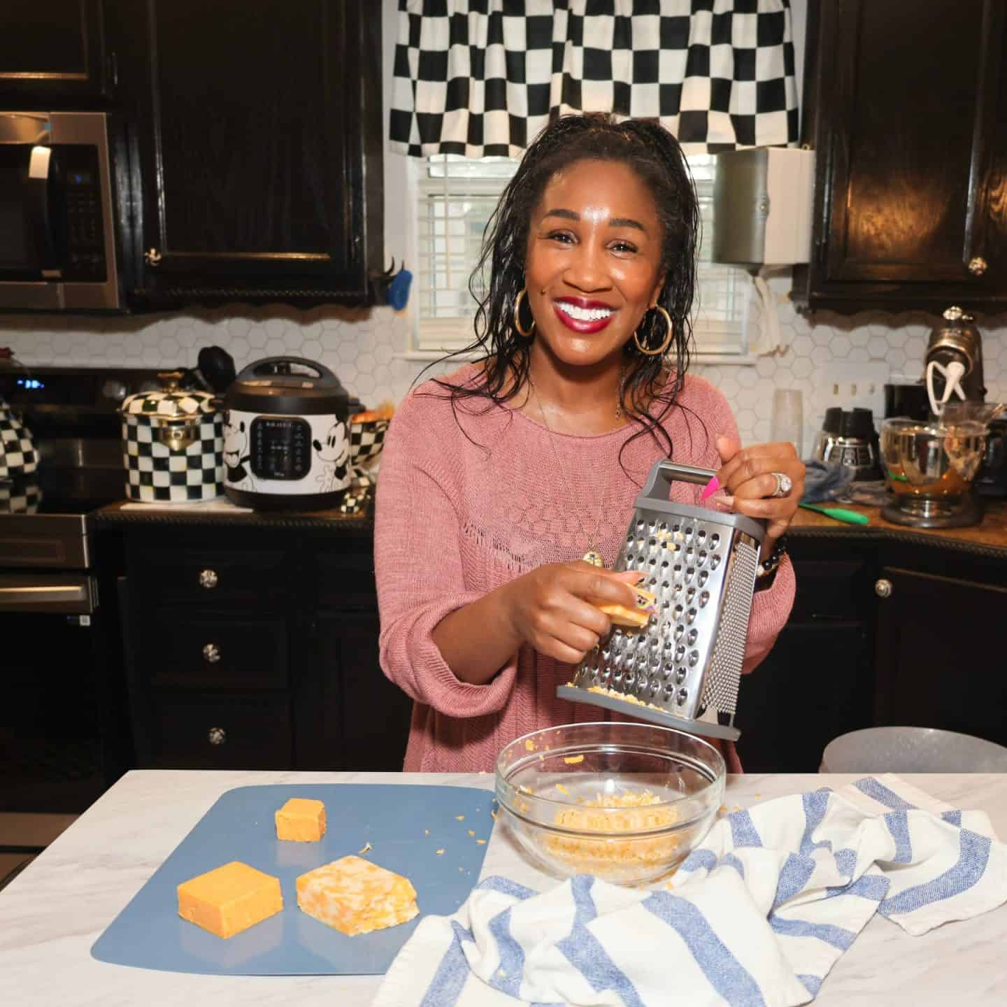 Shaunda Necole grating block cheese into a glass bowl for her Black folks’ baked macaroni and cheese recipe from The Soul Food Pot®.