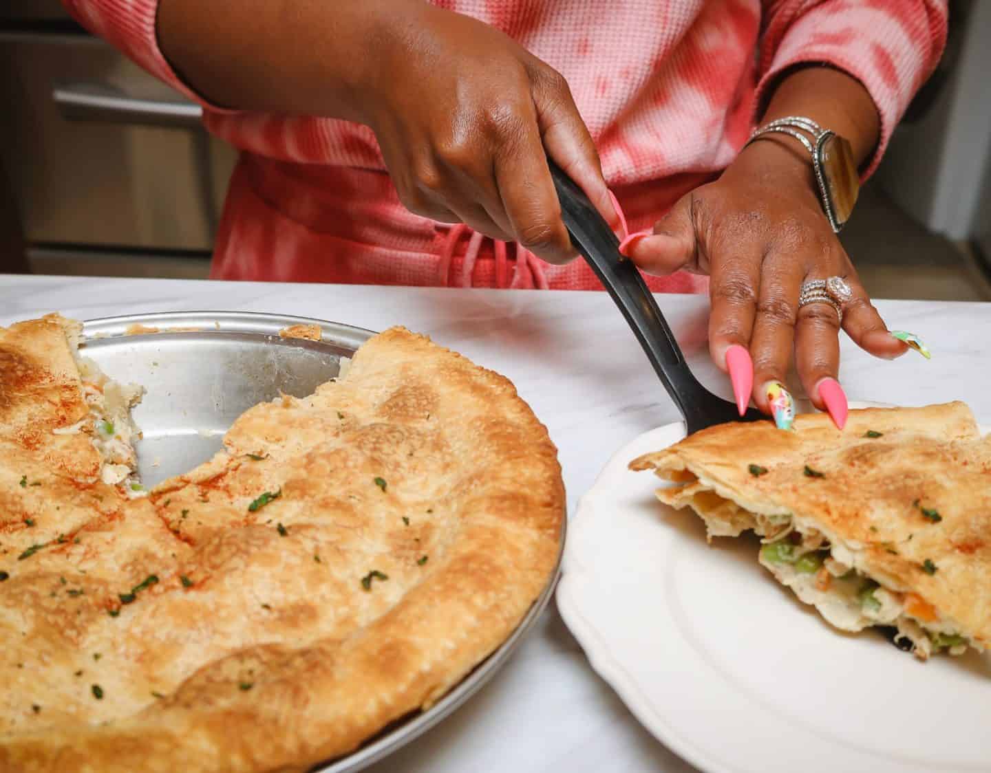 Shaunda Necole serving a slice of homemade chicken pot pie with flaky golden crust and creamy chicken, peas, and carrots for The Soul Food Pot®.