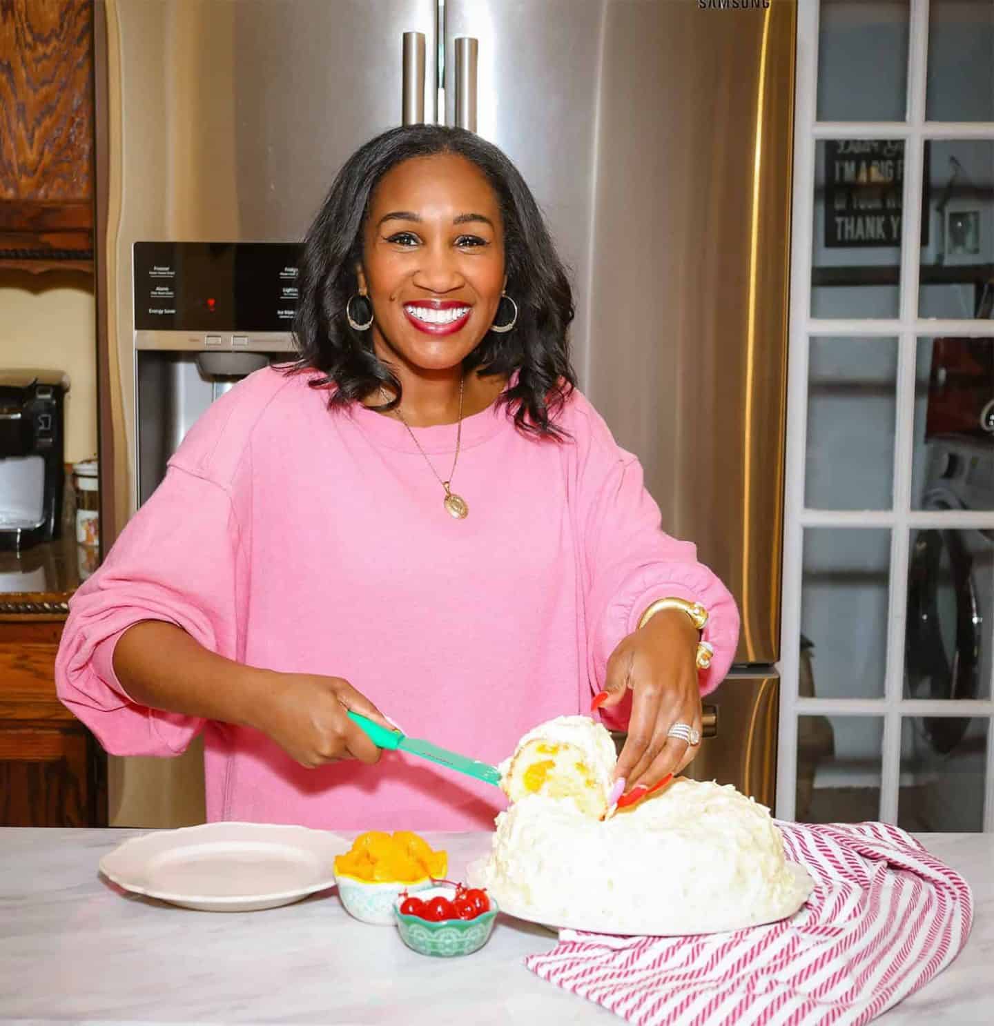 Shaunda Necole is serving creamy Southern ambrosia salad with mandarin oranges and cherries in her home kitchen, an overlooked Labor Day favorite from The Soul Food Pot®.