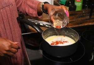 adding seasonings to a milk-based sauce
