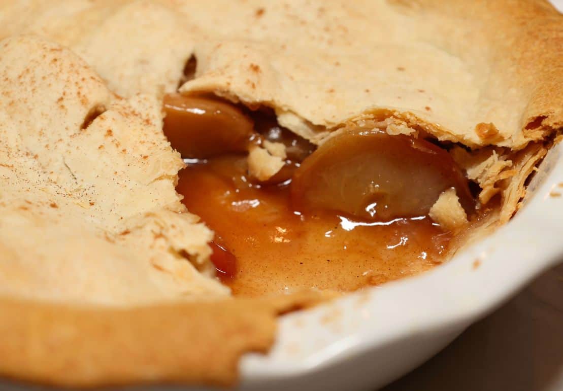 Close-up of The Soul Food Pot® apple pie with tender apple slices in a thickened cinnamon filling beneath a flaky golden crust.
