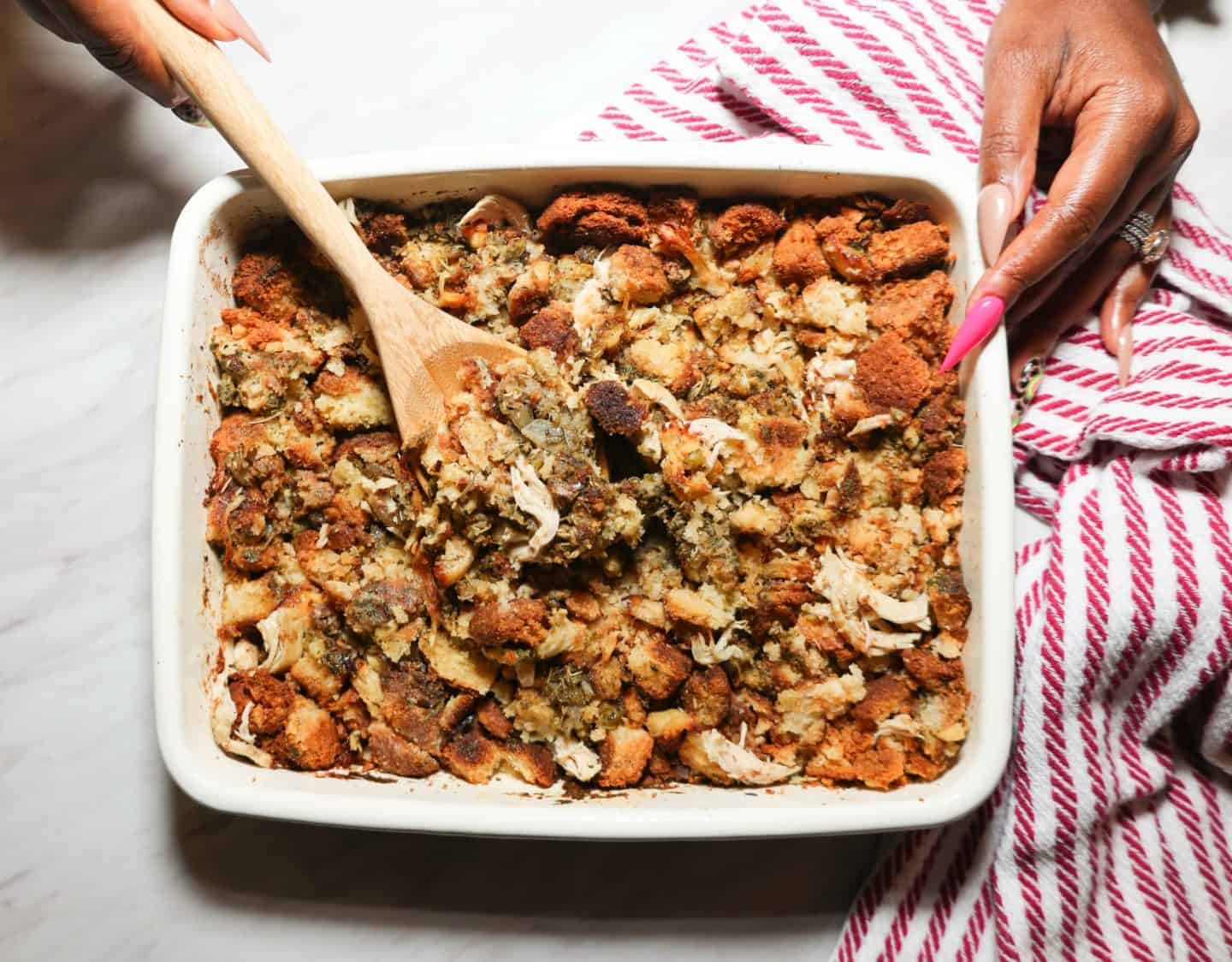 Freshly baked Black folks chicken and dressing with golden cornbread, shredded chicken, onion, celery, and herbs being served from the baking dish, from The Soul Food Pot®.