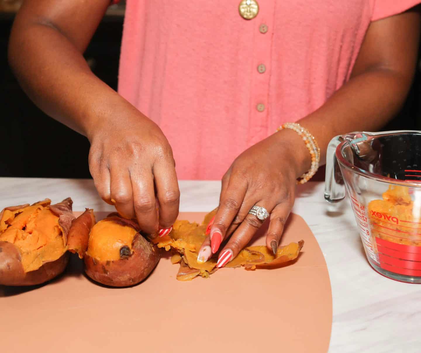 Shaunda Necole removes the skins from cooked sweet potatoes before preparing smooth sweet potato pie filling for The Soul Food Pot®.