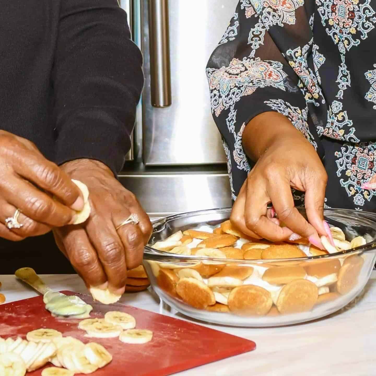 Layering Nilla Wafers and banana slices by hand to build The Soul Food Pot's classic Black folks’ Southern banana pudding with even layers for the perfect texture.