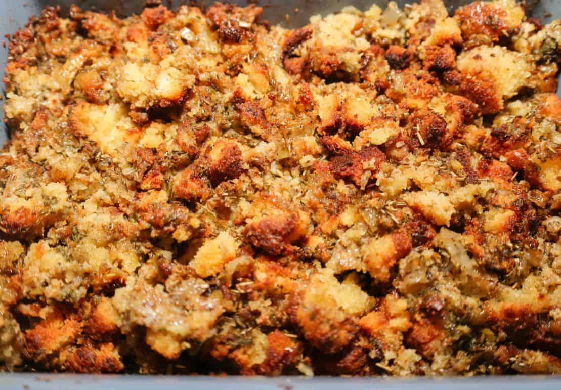 Close-up of The Soul Food Pot® cornbread dressing with moist seasoned cornbread, golden edges, herbs, onion, and celery.