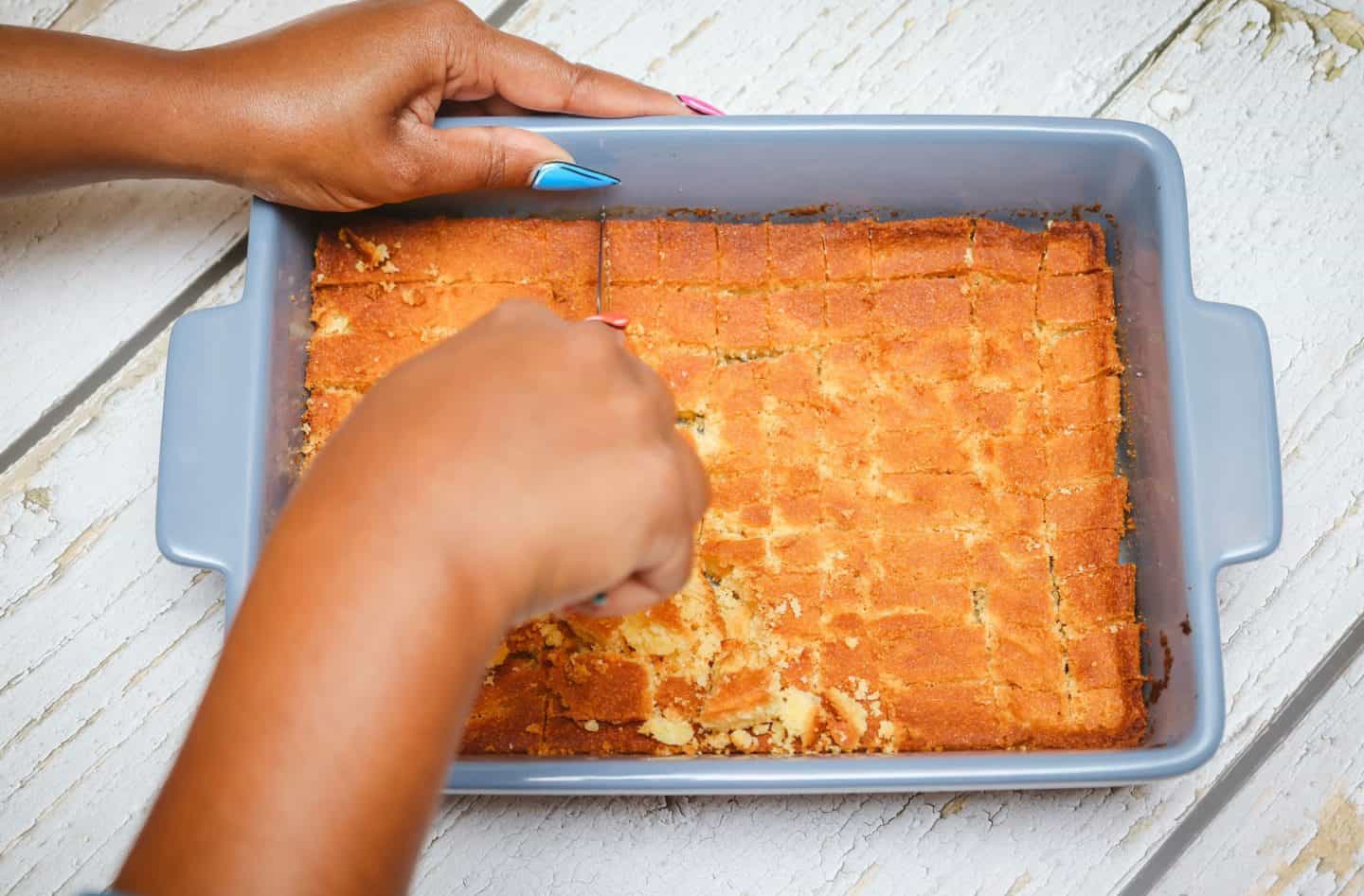 Cutting homemade cornbread into cubes directly in the baking dish for The Soul Food Pot® cornbread dressing recipe.