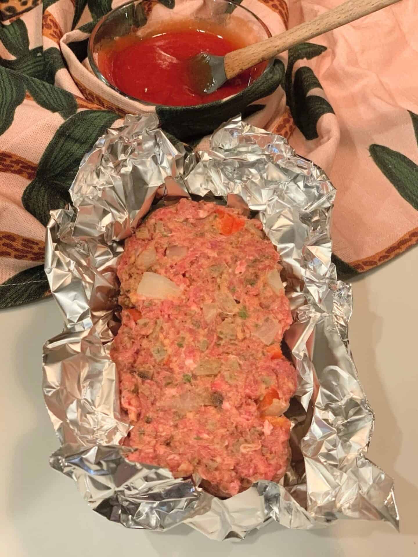 Hand-formed soul food meatloaf shaped inside an aluminum foil cradle as an alternative when a loaf pan is not available.