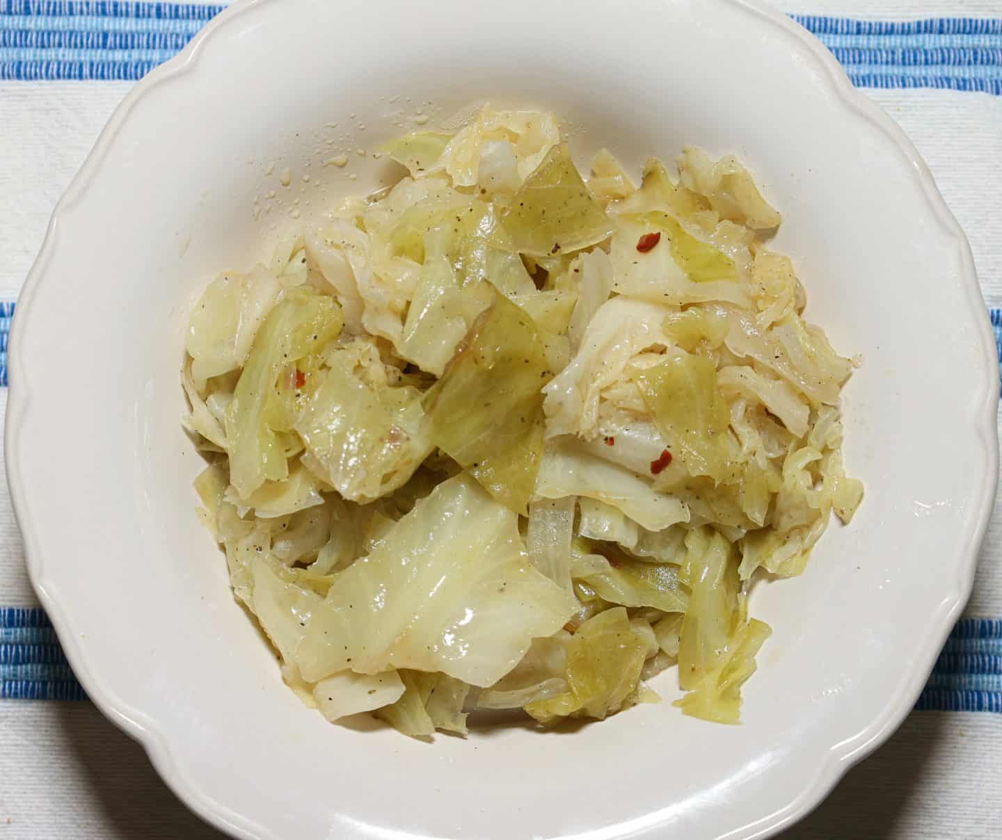 Black folks’ soul food cabbage served in a white bowl, with tender seasoned leaves that still hold their shape after Shaunda’s covered-then-uncovered two-stage cook.