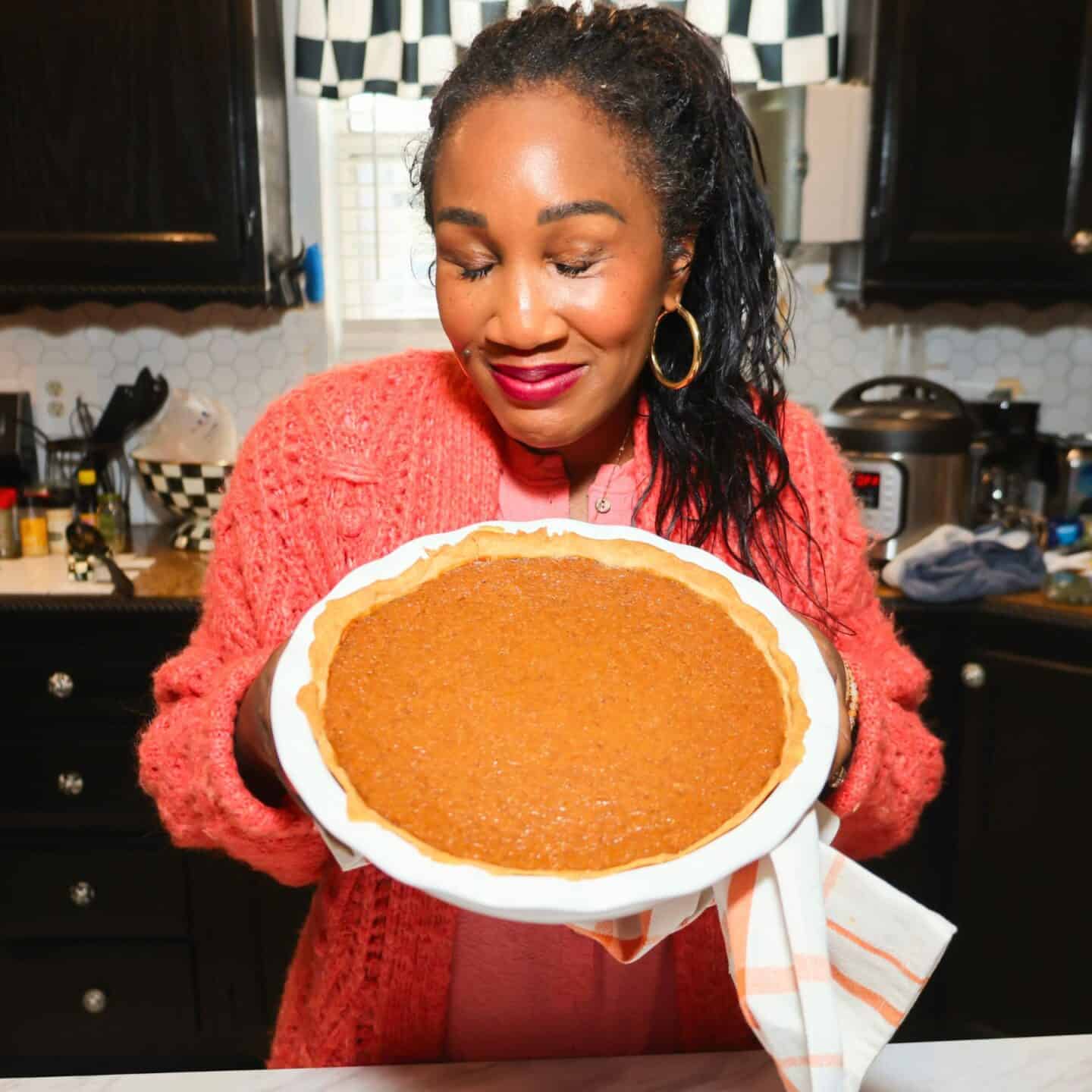 Shaunda Necole holding a homemade sweet potato pie in her kitchen, an essential dessert on her soul food Thanksgiving table for The Soul Food Pot®.