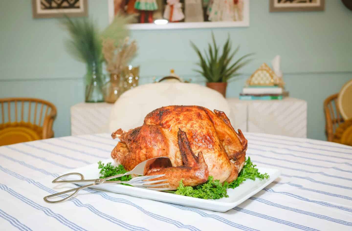 Seasoned roasted Thanksgiving turkey on a white platter at the table, the centerpiece of Shaunda Necole’s soul food Thanksgiving dinner for The Soul Food Pot®.
